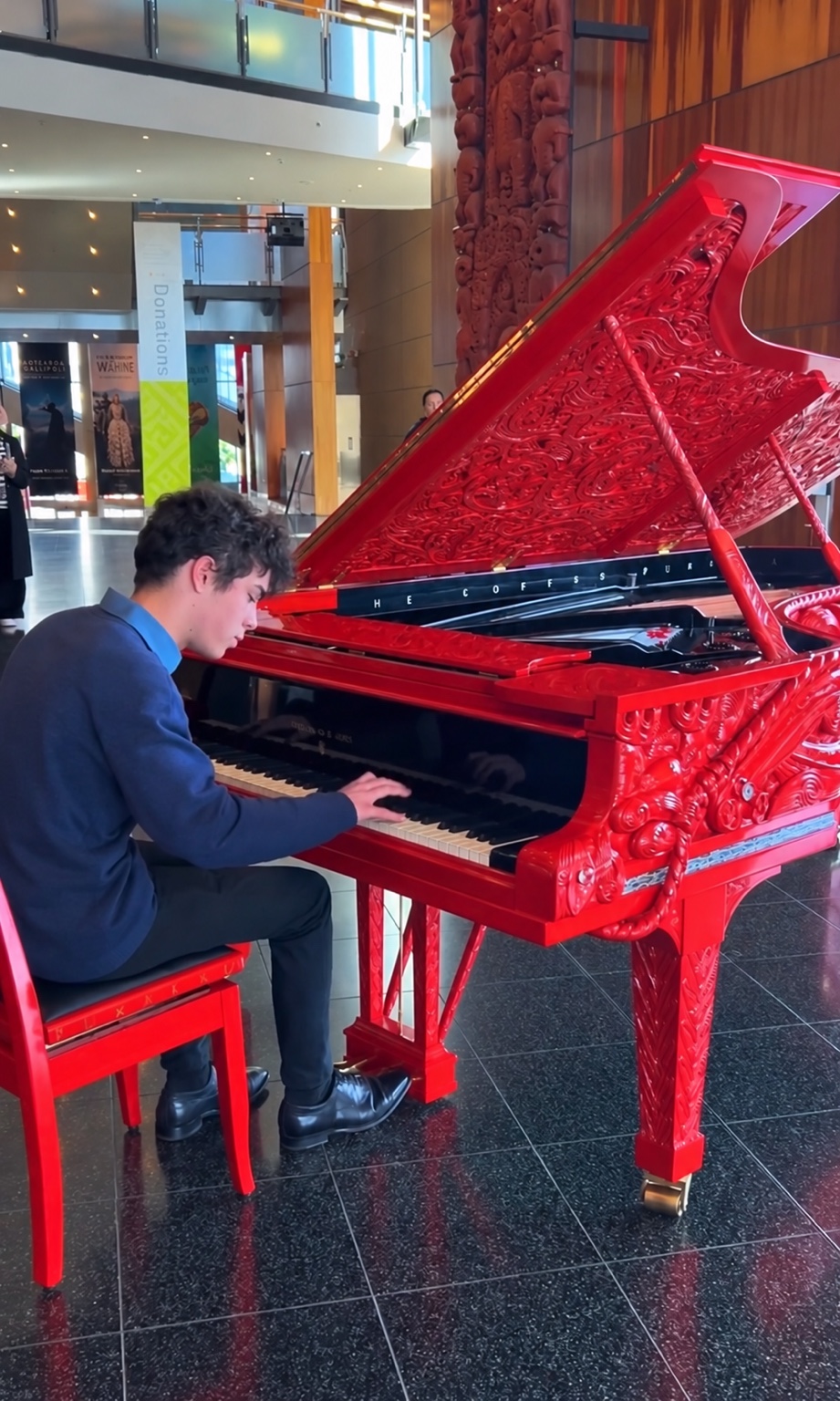 Benjamin Carter playing an intricately carved red grand piano